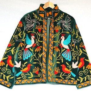 May include: A dark green velvet jacket with colorful embroidered birds and floral patterns. The jacket has a high collar, a zipper closure, and long sleeves. The embroidery features birds with blue, red, and yellow accents, and the jacket is approximately 30 inches long.