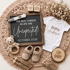 以下が含まれることがあります： 「THE BEST THINGS IN LIFE ARE UNEXPECTED! OCTOBER 2026」と書かれた黒板、白いベビー服に「Baby Anderson」、ベビーシューズ、木製のガラガラ、そして「OH BABY」と書かれた木製のサインが写った妊娠発表。