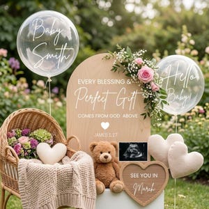 Puede incluir: Un letrero de madera con el texto "Every Blessing & Perfect Gift Comes From God Above" y "James 1:17". El letrero está decorado con flores, globos, un oso de peluche y una ecografía del bebé. Los globos dicen "Baby Smith" y "Hello Baby!"