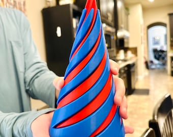 May include: A blue and red spiral-shaped decorative object. The object is held by a person and has a conical shape with alternating blue and red bands. The top of the object is red.