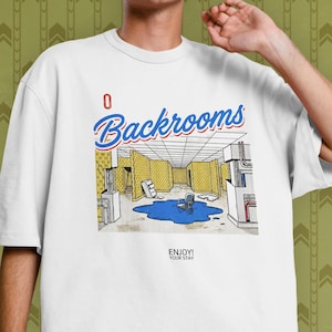Peut inclure: Un t-shirt blanc à manches courtes avec une impression graphique représentant une pièce aux murs jaunes, une flaque bleue et une chaise. Le texte indique Backrooms en bleu et rouge, avec en dessous la mention ENJOY! YOUR STAY en noir.