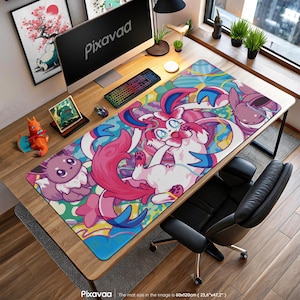 Può includere: Un colorato tappetino per scrivania con un design vivace con personaggi dei cartoni animati rosa, blu e bianchi. Il tappetino misura 60x120cm ed è posizionato su una scrivania in legno con computer, tastiera e mouse. Il logo Pixavaa è visibile.