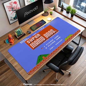 Könnte beinhalten: Blaues Schreibtisch-Pad mit dem Super Mario Bros. Logo. Das Pad hat ein Retro-Videospiel-Design mit einer pixeligen Landschaft und dem Titel des Spiels in Orange und Weiß. Das Pad misst 60cm x 120cm.