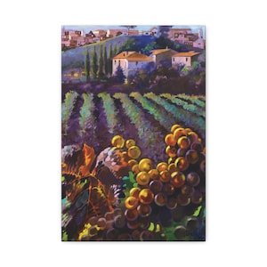 May include: A canvas print of a vineyard scene. The artwork depicts rows of grapevines in a field, with a village on a hillside in the background. The grapes are yellow and purple, and the sky is blue.