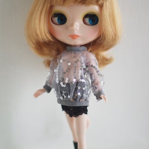 May include: A doll with blonde hair wearing a grey sequined top, a black lace skirt, and black boots.