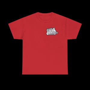 May include: A red t-shirt featuring a small, stylized graphic on the upper left chest. The graphic is a white and gray bubble-style text that reads "GAP CLUB". The shirt is made of a soft material.