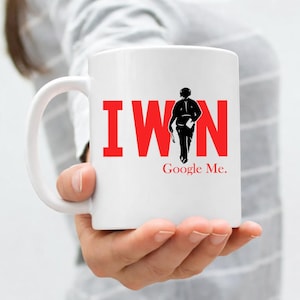 May include: White ceramic mug with the text "I WIN" in red block letters and a black silhouette of a person. Below the silhouette, the text "Google Me" is printed in black.
