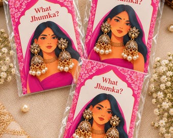 Op de afbeelding: Drie sets goudkleurige jhumka-oorbellen met gedetailleerd metaalwerk en witte parels, elk gepresenteerd op een kaart met een illustratie en de tekst What Jhumka? in een doorzichtige plastic beschermhoes verpakt.