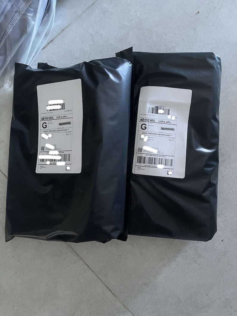 May include: Two black poly mailer shipping packages with white address labels. The packages are sealed and ready for shipment. The labels have barcodes and text.