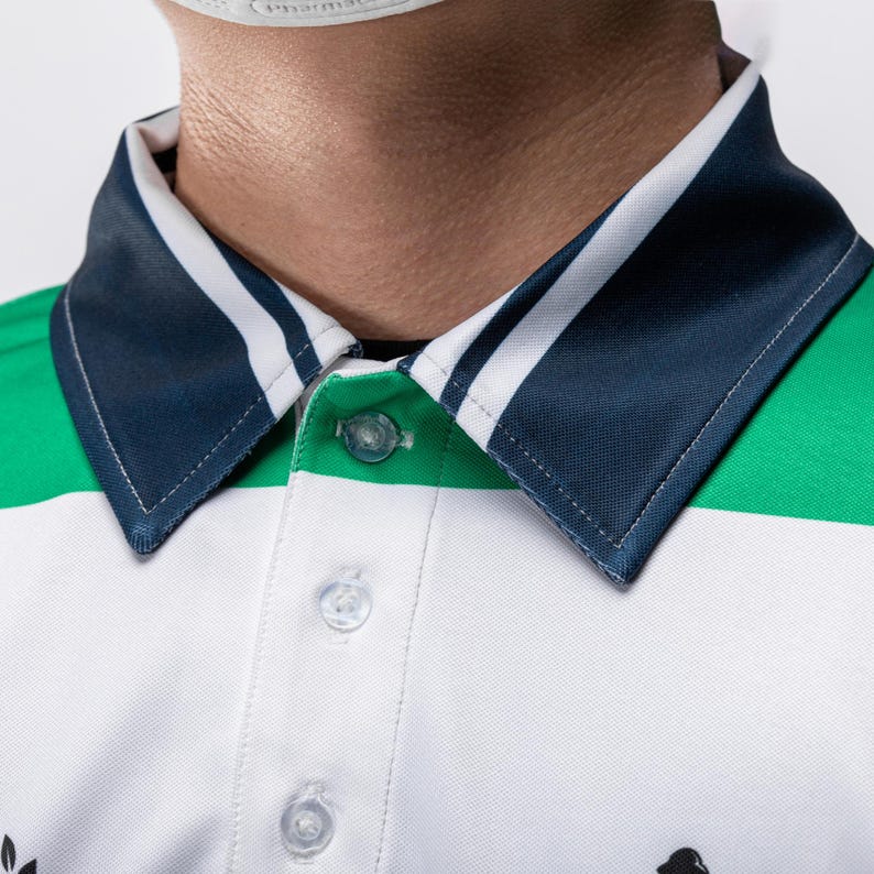May include: A polo shirt featuring a white base with horizontal green stripes and a dark blue collar accented by two thin white stripes. The shirt includes a button-down placket with three clear buttons and visible stitching along the collar edges.