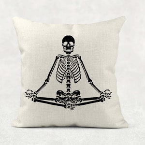 May include: A black and white illustration of a skeleton sitting in a yoga pose on a white pillow.
