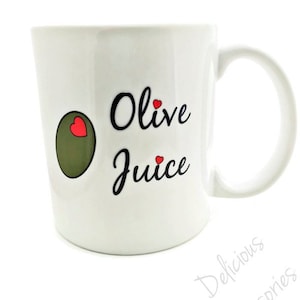 May include: White ceramic mug with a green olive and red hearts graphic and the text "Olive Juice" in black cursive font.