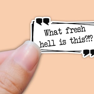 May include: A white sticker with black text and borders. The text reads "What fresh hell is this??" with quotation marks at the beginning and end of the text.