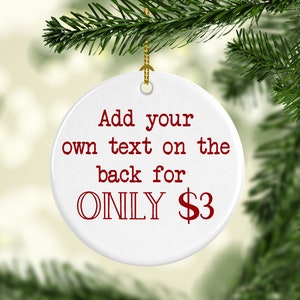 K&ouml;nnte beinhalten: Ein wei&szlig;er, runder Weihnachtsschmuck mit dem roten Text "Add your own text on the back for ONLY $3". Der Schmuck h&auml;ngt an einem goldenen Faden und ist von gr&uuml;nen Tannenzweigen umgeben.