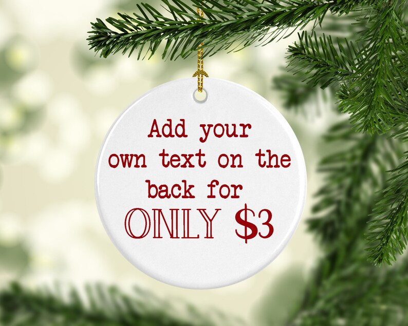 K&ouml;nnte beinhalten: Ein wei&szlig;er, runder Weihnachtsschmuck mit dem roten Text "Add your own text on the back for ONLY $3". Der Schmuck h&auml;ngt an einem goldenen Faden und ist von gr&uuml;nen Tannenzweigen umgeben.