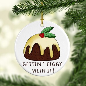 May include: White ceramic Christmas ornament with a cartoon illustration of a Christmas pudding with a yellow icing and a green holly sprig on top. The text "Gettin' Figgy With It!" is printed below the pudding.