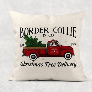 May include: A white throw pillow with a black and white border collie dog driving a red vintage pickup truck with a Christmas tree in the back. The text on the pillow reads "BORDER COLLIE & CO EST 1972 Christmas Tree Delivery".