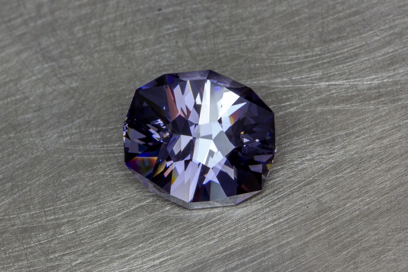 May include: A faceted purple gemstone with a star-like pattern in the center.