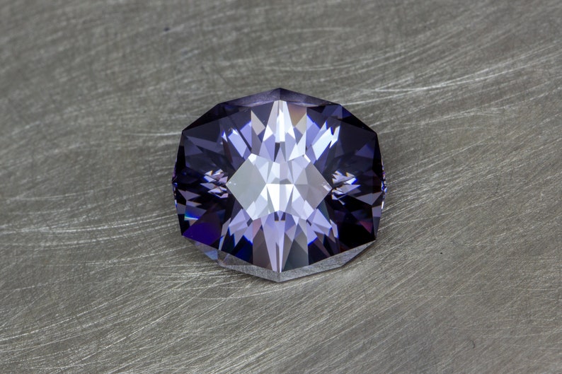 May include: A faceted purple gemstone with a star-like pattern in the center.