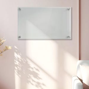May include: A rectangular clear acrylic dry erase board mounted to the wall with four silver-toned metal standoffs at each corner. The board features a smooth, transparent surface designed for writing and is positioned horizontally on the wall.
