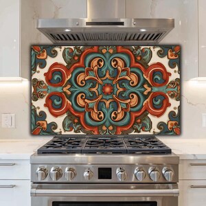 May include: A rectangular kitchen backsplash panel featuring a symmetrical, ornate pattern in shades of burnt orange, teal, and cream. The design consists of repeating scrollwork and floral-inspired motifs arranged in a central, balanced layout.