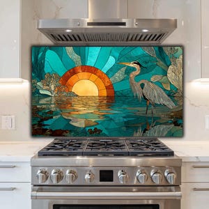 May include: A decorative kitchen backsplash featuring a stained-glass style design. The artwork depicts a heron standing in water with a sunset in the background. The color palette includes shades of teal, orange, and gold.