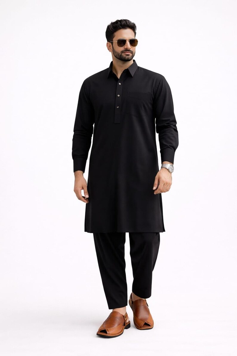 May include: A black kurta pajama set. The long-sleeved kurta has a collared neckline and a buttoned placket. The matching pajama pants are straight-legged. The outfit is paired with brown leather sandals. The person is wearing sunglasses and a watch.