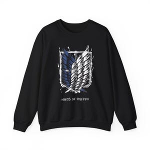May include: Black crewneck sweatshirt featuring a white and blue emblem with a wing design. The words "WINGS OF FREEDOM" are printed in white below the emblem. The sweatshirt is made of a soft material.
