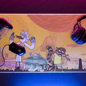 Peut inclure: Tapis de souris de jeu rectangulaire avec les personnages de dessins animés Rick et Morty. Le tapis a un fond jaune avec un design coloré, une souris noire, une manette noire et un casque noir. Le tapis a un bord lumineux.
