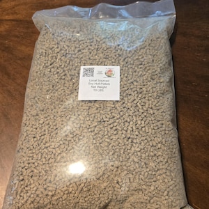 May include: A transparent plastic bag filled with light brown soy hull pellets. A white label on the bag reads "Local Sourced Soy Hull Pellets" and "Net Weight 4.5 kg."