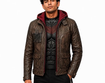 May include: A brown distressed leather jacket featuring a maroon hooded lining, a front zip fastening, two lower flap pockets, and one chest flap pocket. The jacket is worn over a black textured shirt with a dark red chest emblem and black trousers.