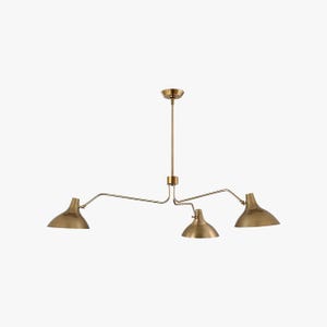 May include: A brass-coloured, three-light pendant light fitting. The fixture features a central stem with three curved arms, each holding a downward-facing, bell-shaped shade. The design is minimalist and modern, suitable for various interior styles.