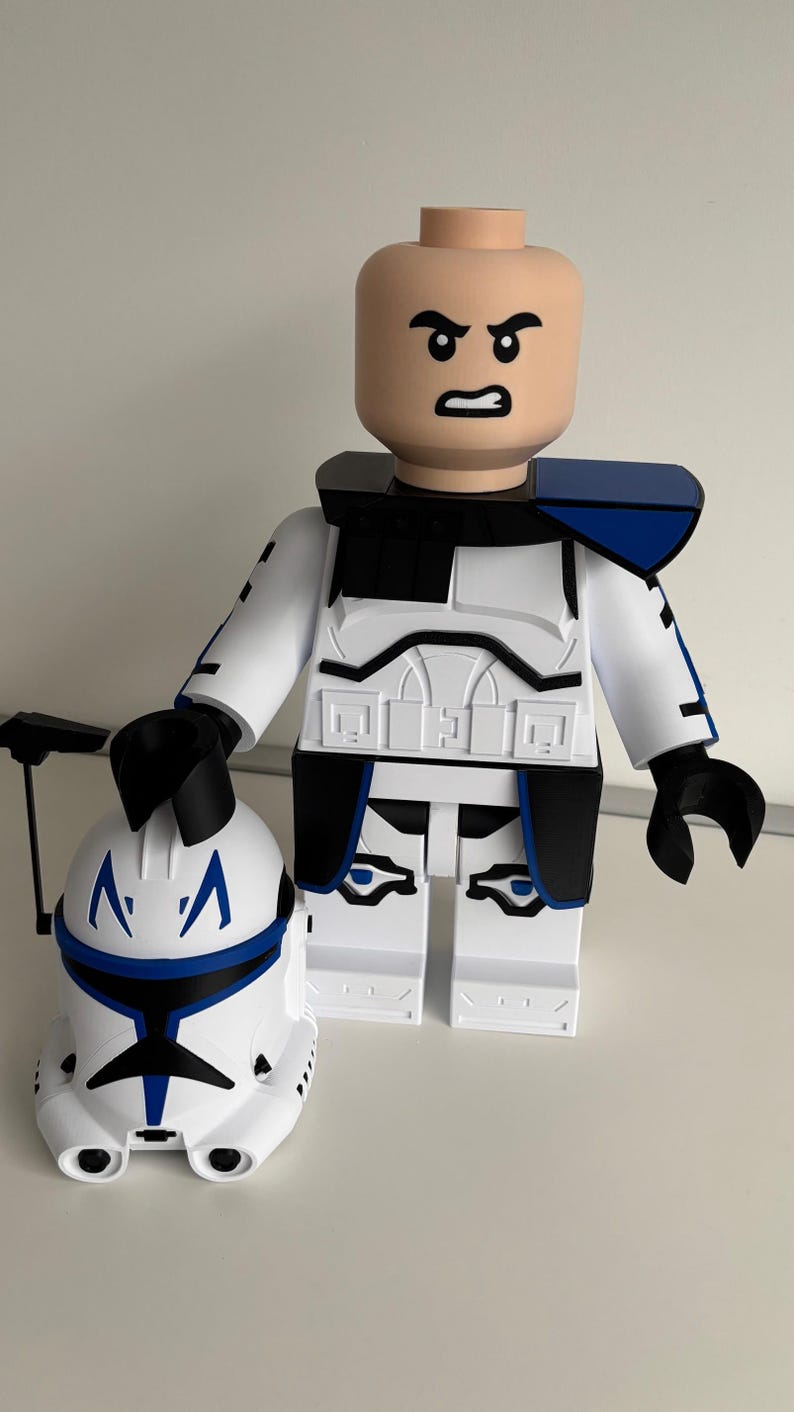 May include: A large, white and blue clone trooper action figure with a matching helmet. The figure has a bald head with an angry expression, black accents, and blue shoulder pads. The helmet is held in the left hand.