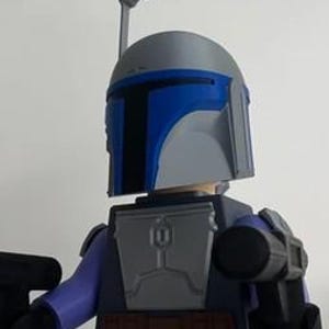 Op de afbeelding: Een plastic speelgoedfiguur met een grijze en blauwe helm met een omhoogstaande antenne, een grijze borstplaat en paarse armen. Het figuur houdt twee zwarte blasters vast, één in elke hand, en draagt een bruine gereedschapsriem om de taille.