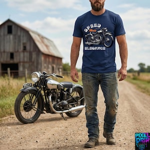 May include: Navy blue t-shirt with the text "Speed Meets Elegance" and a vintage motorcycle graphic. A classic black and silver motorcycle is parked on a dirt road. The scene includes a weathered barn and a man in jeans.