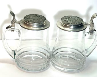 Paar vintage helderglazen bierkroezen met tinnen deksels en schelpduim