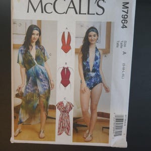 May include: McCall's sewing pattern M7964 featuring designs for swimwear and a cover-up. The pattern includes illustrations of a red swimsuit, a blue swimsuit, and a floral cover-up. Size A, (S-M-L-XL).
