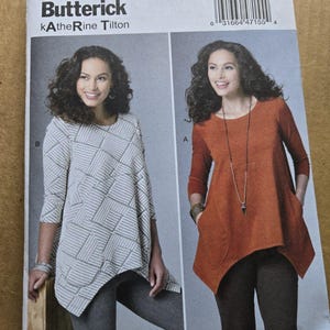 May include: A Butterick B6492 sewing pattern envelope by Katherine Tilton featuring two tunic tops. One is a white top with a gray geometric line pattern, and the other is a solid rust-colored top. Both have three-quarter sleeves and pockets.