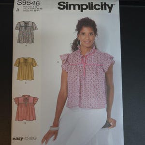 May include: Simplicity sewing pattern S9546 features a woman wearing a pink paisley top. The pattern includes three blouse designs with ruffled sleeves. The text "easy-to-sew" and "Designed and printed in USA" are visible.
