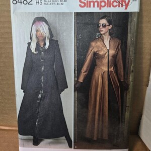May include: Simplicity sewing pattern 8482 for a long coat with a front zipper. The package shows two variations: a black hooded coat and a metallic bronze coat with a high collar. The pattern includes sizes U.S. 6-14, Euro 32-40, and French 34-42.