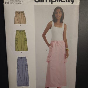 May include: Simplicity sewing pattern S9891 for skirts. The pattern includes three skirt styles: a plaid mini skirt, a green cargo skirt, and a long blue skirt. The pattern size is U.S. 6-14.