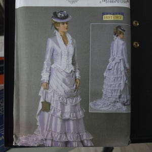 May include: A Butterick sewing pattern featuring a historical costume design. The illustration shows a woman in a lavender dress with ruffles and a matching hat. The pattern includes the text "B6692" and "HISTORY".