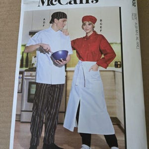 May include: McCall's sewing pattern envelope M8332 for chef uniforms. The front shows a white short-sleeve chef coat, black and white striped pants, a red chef coat, a white apron, and matching hats. The text includes McCall's, M8332, and size A.
