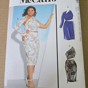 May include: A McCall's M8331 sewing pattern envelope featuring a white dress with a gold leaf print, a single long sleeve, and a circular cutout at the waist. The envelope displays three design variations, size W3, and text including Designed and printed in USA.