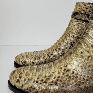 Puede incluir: Un par de botines con estampado de piel de serpiente en tonos beige, marr&oacute;n y negro. Los botines tienen punta y una correa en el tobillo. Las suelas son de color marr&oacute;n oscuro.