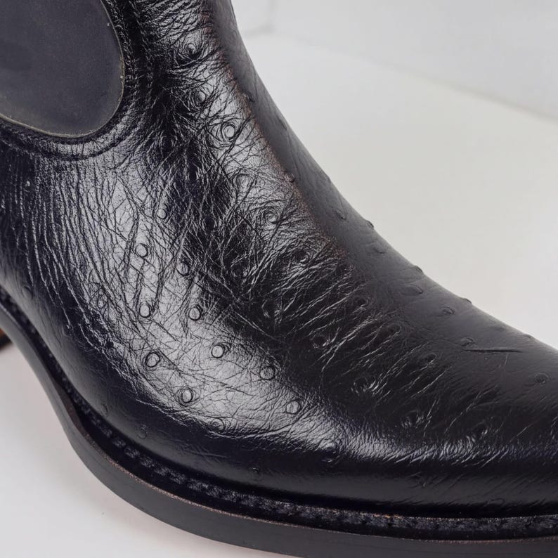 A close-up view of a black leather boot with a distinctive ostrich-like texture.
