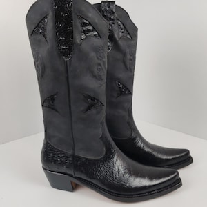 A pair of black cowboy boots with a distinctive design on the sides.