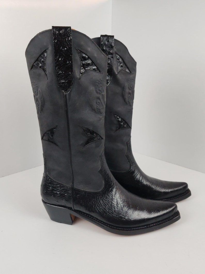 A pair of black cowboy boots with a distinctive design on the sides.
