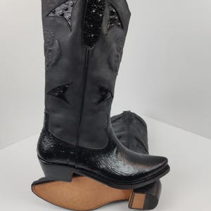 A pair of black leather cowboy boots with a distinctive design on the sides.