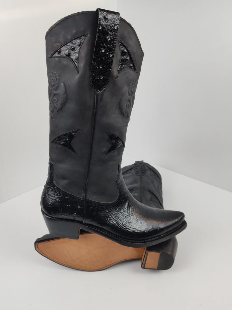 A pair of black leather cowboy boots with a distinctive design on the sides.